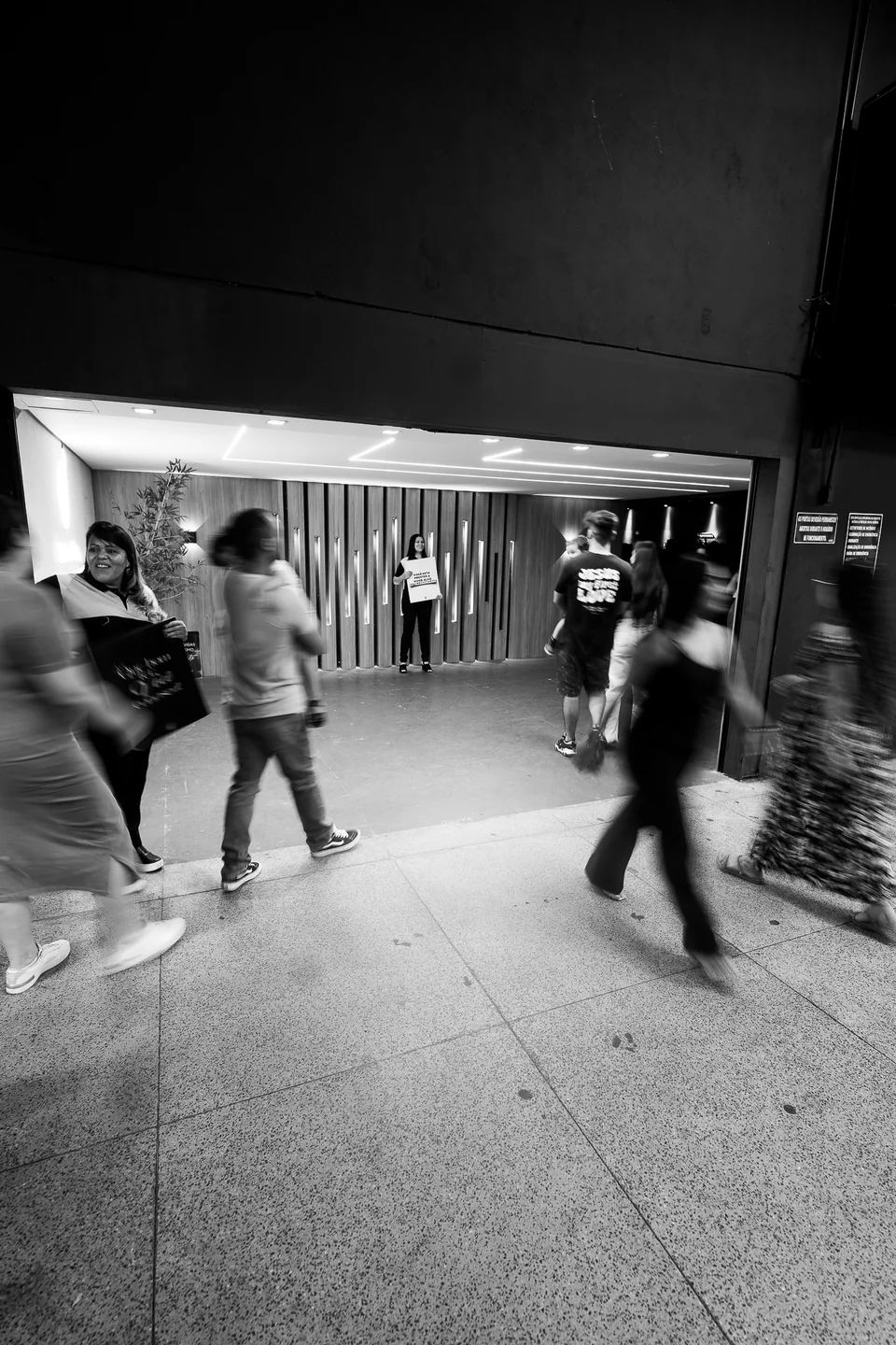Pessoas chegam à igreja e são recebidas na entrada, em uma fotografia em preto e branco.